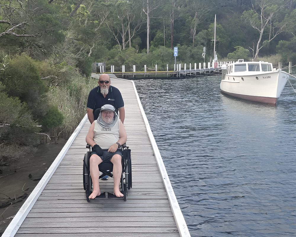 A man and woman in wheelchairs on a dock.