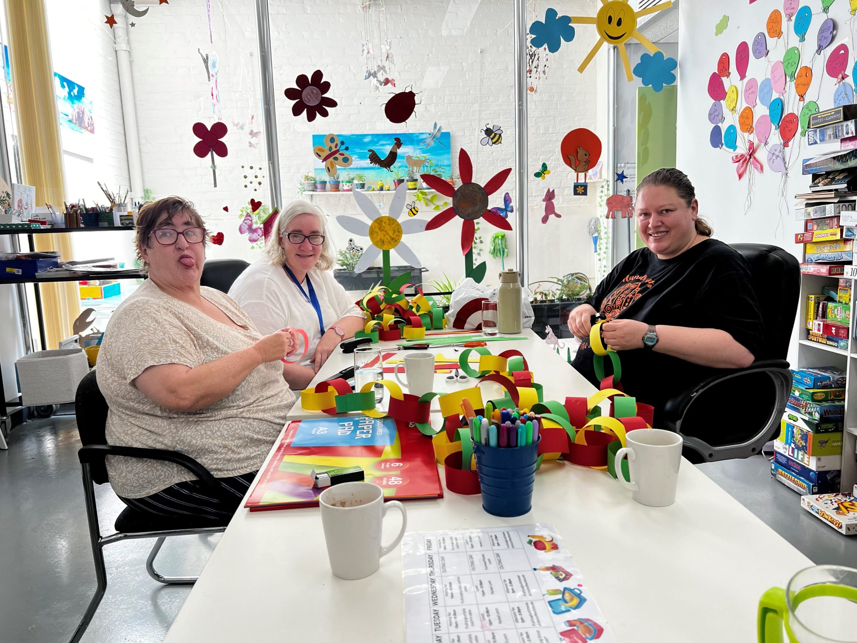Three people sitting at a table with some paper flowers