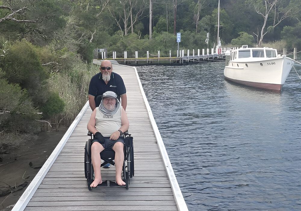 A man and woman in wheelchairs on a dock.